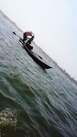 Man on boat in sea against clear sky