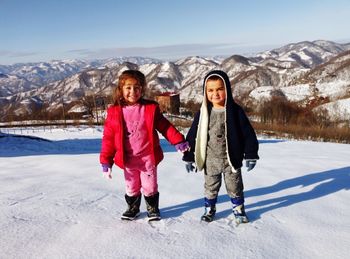 Portrait of girls standing on snow covered land