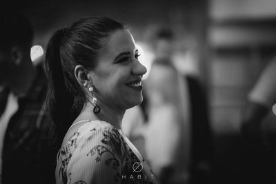 Side view of smiling young woman wearing earring looking away