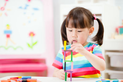 Cute girl holding toy while sitting at home