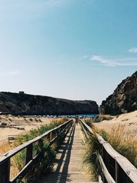 Footpath leading towards mountain against sky