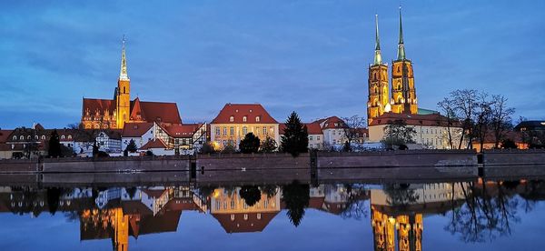 Reflection of buildings in river against sky in city