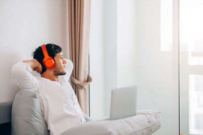 Side view of young man using mobile phone at home