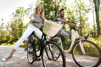 Happy couple riding bicycle against trees