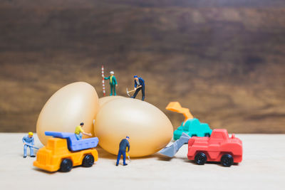 Close-up of figurines with eggs and toy trucks on table