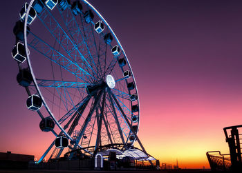 Low angle view of ferris wheel against sky at sunset