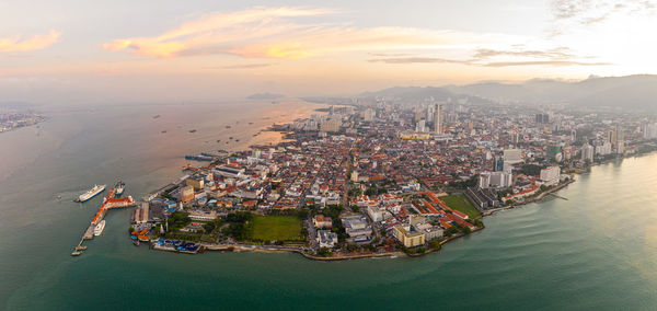 High angle view of buildings by sea against sky during sunset