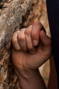 Close-up of cropped hand on stone wall