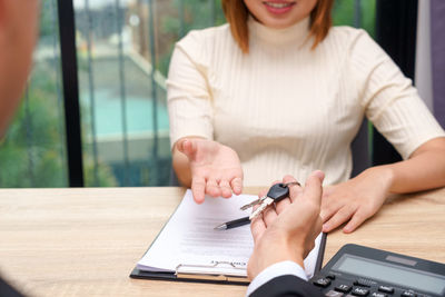 Midsection of woman using mobile phone while sitting on table