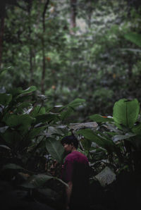 Midsection of woman standing by tree in forest