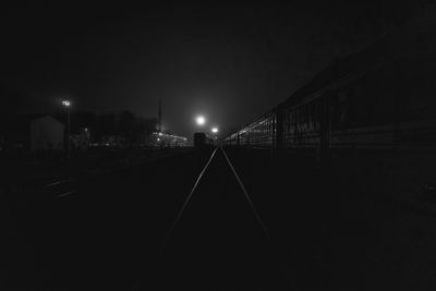 Illuminated railroad tracks against sky at night