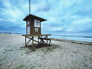 Lifeguard hut on beach against sky