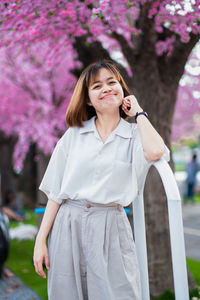 Portrait of beautiful woman standing against red flowering plants