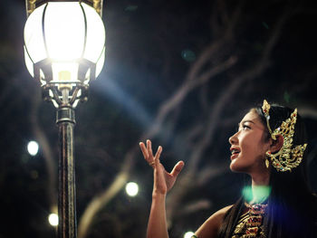 Traditional dancer looking at illuminated electric lamp