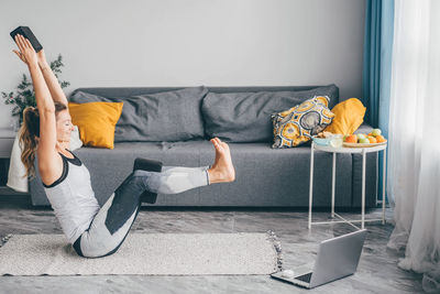 Low section of woman sitting on sofa at home
