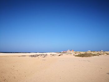 Scenic view of beach against clear blue sky