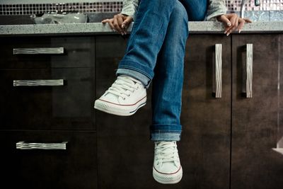 Low section of woman sitting on kitchen counter