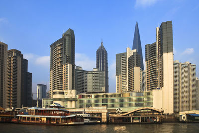 Modern buildings by canal against sky in city