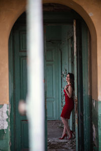 Side view of woman standing against door