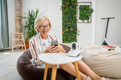 Young woman using mobile phone while sitting at home