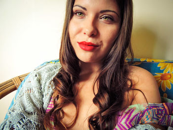 Young woman sitting on sofa against wall