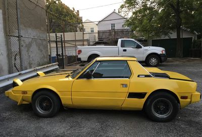 Yellow car parked on street against buildings