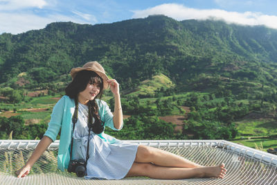 Rear view of woman sitting on mountain against trees