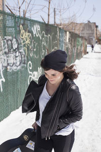 Young woman carrying a guitar case through the snow