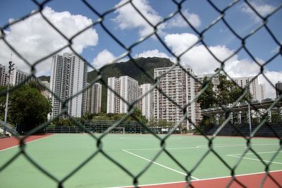 Residential buildings against clear blue sky and fence