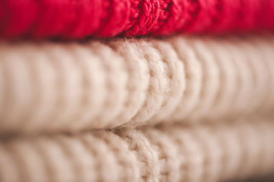 Stack of bright color knitted clothes on shelf in store close up. warm and cozy colorful sweaters. 