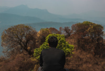 Rear view of man on mountain against sky