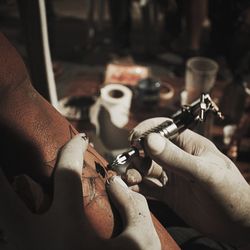 Cropped hands of artist tattooing customer