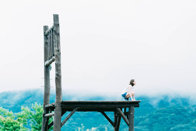 Man sitting on seat against sky