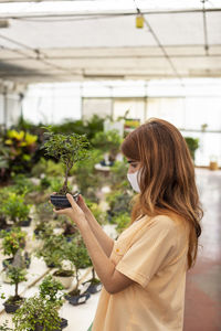 Side view of woman holding plants