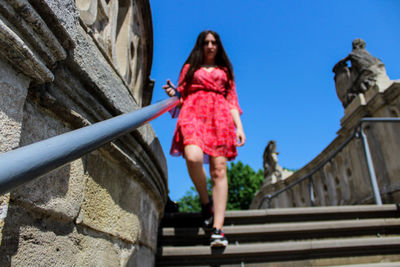 Low angle view of woman walking on staircase in city during sunny day