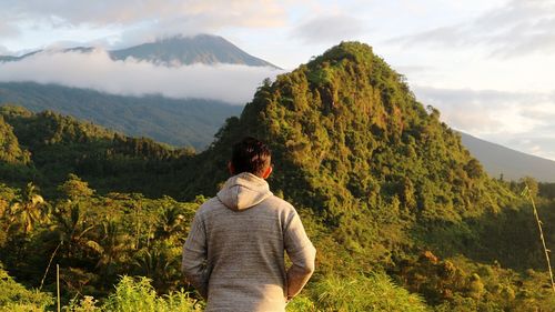 Rear view of man standing on mountain against sky