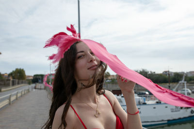 Portrait of smiling woman standing by pink flag at harbor