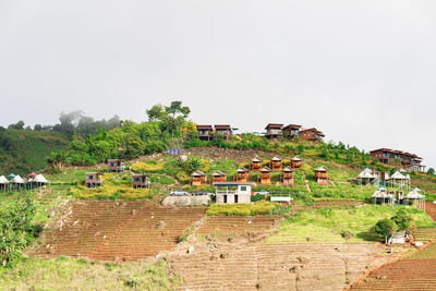 Houses and trees on field against sky