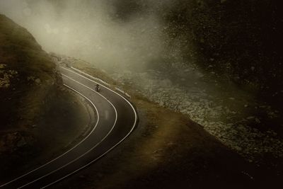 High angle view of man riding motorcycle on road in foggy weather