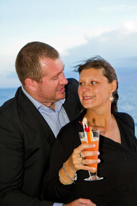 Loving mature couple standing by sea during sunset