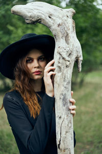 Portrait of young woman standing against trees