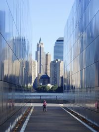 Child standing in between skyscrapers in city