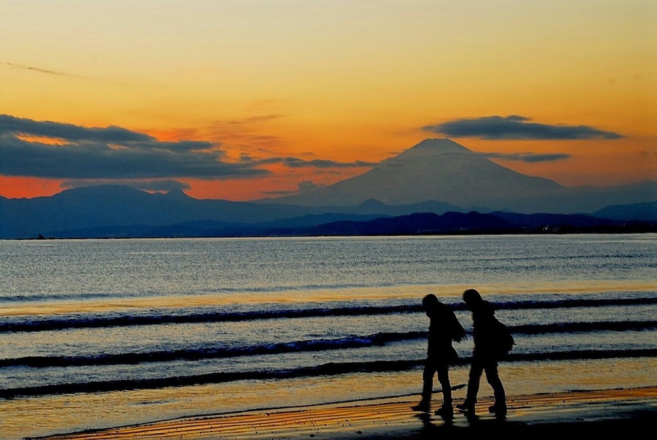 sunset, silhouette, sea, water, lifestyles, leisure activity, beach, men, sky, orange color, scenics, beauty in nature, tranquil scene, shore, tranquility, togetherness, vacations, nature