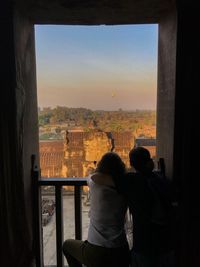 Rear view of people looking at cityscape through window