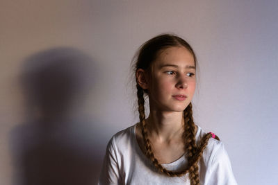 Portrait of young woman standing against wall