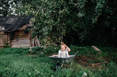 A cute girl is sitting in a cart under an apple tree in the courtyard of her village house