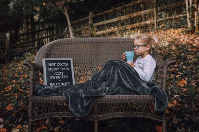 Girl having drink while sitting on bench