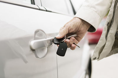 Midsection of man holding white car