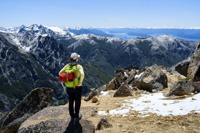 Rear view of woman looking at view while standing on mountain during winter