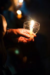 Close-up of hand holding lit candle